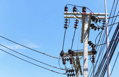 Yazın elektrik direğinde elektrik kabloları olan bir inşaat alanında bitmemiş çimento bina.