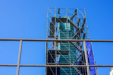 Mavi gökyüzüne karşı inşaat iskelesi. İşçi koruma kavramı