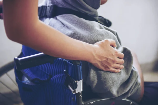Hastayla tekerlekli sandalye iten hemşire. Genç engelli insanlar tekerlekli sandalyede oturuyor. Gerçek hayatta felç ve sakatlık. Hemşirenin bir adama yardım ederken çekilmiş bir fotoğraf.
