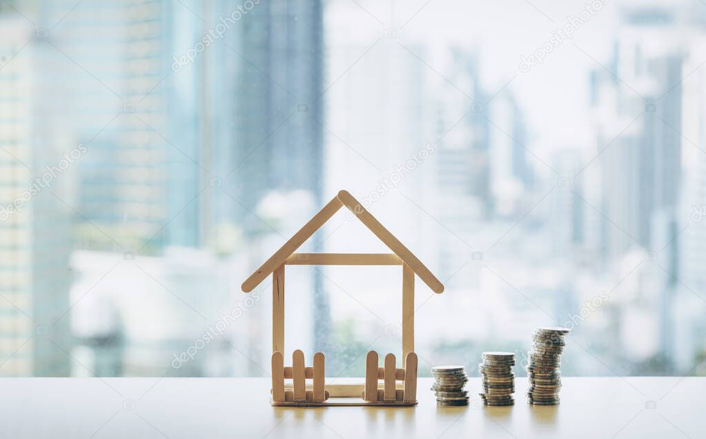 A pile of coins break down. Mini wooden house and row of coin falls. Mortgage and real estate investment or  Insurance finance and investing concept.
