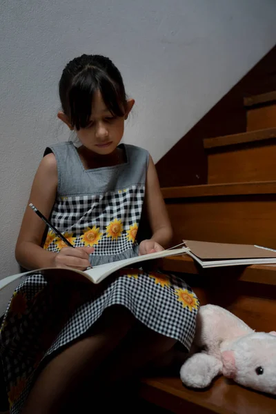 少女は本を書き 家でクッキーを持っている 家庭の概念から学ぶ — ストック写真