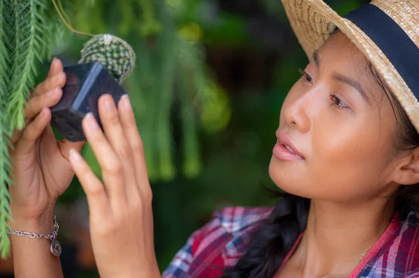 Küçük bir bahçe dükkanında bitkilerle ilgilenen genç bir Asyalı kadın.