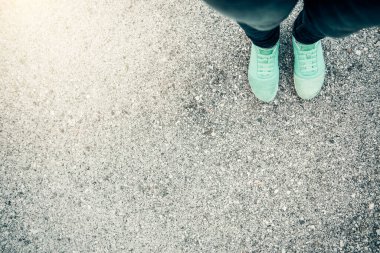 Turistik bacakların üst görüntüsü açık mavi-yeşil ayakkabılar giyip yolda yürümeye devam ederek rüyalara dalmak.