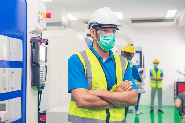 Male industrial engineer or technician worker wear face mask with safety and hard helmet training trainee assistant using control machine operating control CNC machinery at factory Industrial.