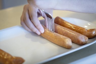 Yakın çekim eller çatal delici ev yapımı sosis kullanır. Aile yemeği hazırla BBQ.