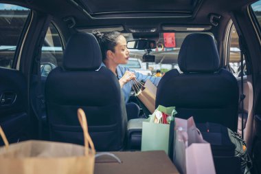Mutlu kadınlar tam kağıt ve alışveriş çantaları. Renkli çanta ve kahverengi kutu bagajda. Satın aldığı ürünü kontrol eden ve ayarlayan kadın. Alışveriş bağımlılığı ya da alışveriş anlayışı.