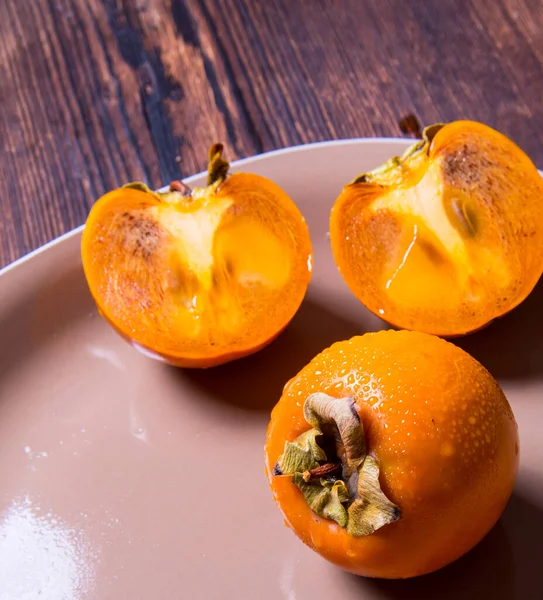 Persimmon Halbiert Und Ganze Persimmon Auf Einem Teller Auf Einem — Stockfoto