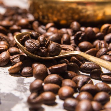 Kahve çekirdekleri kaşıkta masaya saçılmış, yakın plan, mesaj için yer var.