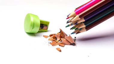 Renkli kalemler ve metal açacağı, beyaz arkaplanda izole edilmiş renkli kalem dosyaları, yakın plan, metin için boşluk