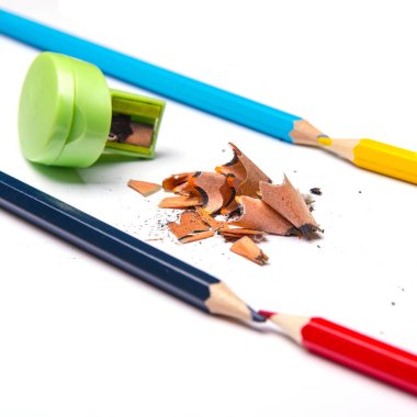 Renkli kalemler ve metal açacağı, beyaz arkaplanda izole edilmiş renkli kalem dosyaları, yakın plan, metin için boşluk