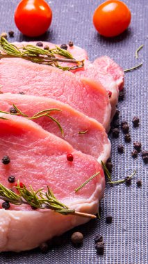 Domuz eti. Siyah pirzola tahtasında taze domuz bifteği ve baharatlı, kiraz domatesli, biberiyeli, biberli, biberli, kopyalama alanlı.