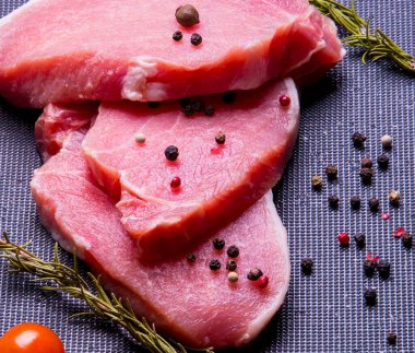 Domuz eti. Siyah pirzola tahtasında taze domuz bifteği ve baharatlı, kiraz domatesli, biberiyeli, biberli, biberli, kopyalama alanlı.