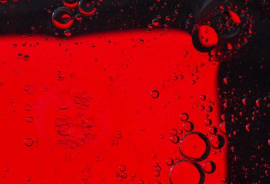 Su yüzeyinde yağ kabarcıkları hareket halinde, kırmızı zemin üzerinde, makro, sıçrama ekranı, şablon, kopyalama alanı