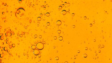 Su yüzeyinde yağ kabarcıkları hareket halinde, sarı-kırmızı bir zemin üzerinde, makro, sıçrama ekranı, şablon, kopyalama alanı