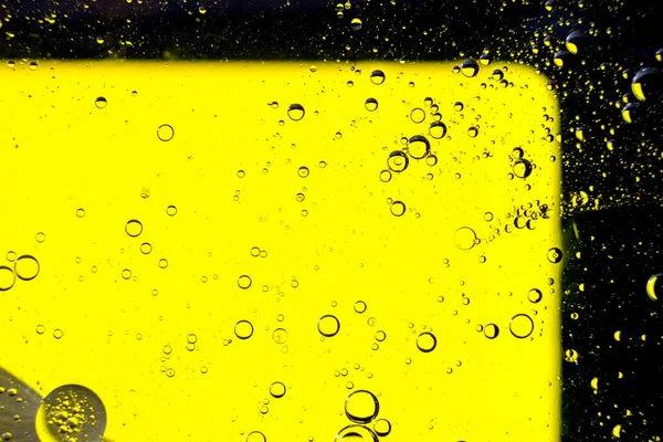 Oil bubbles on the water surface in motion, on a yellow background, macro, splash screen, template, copy space