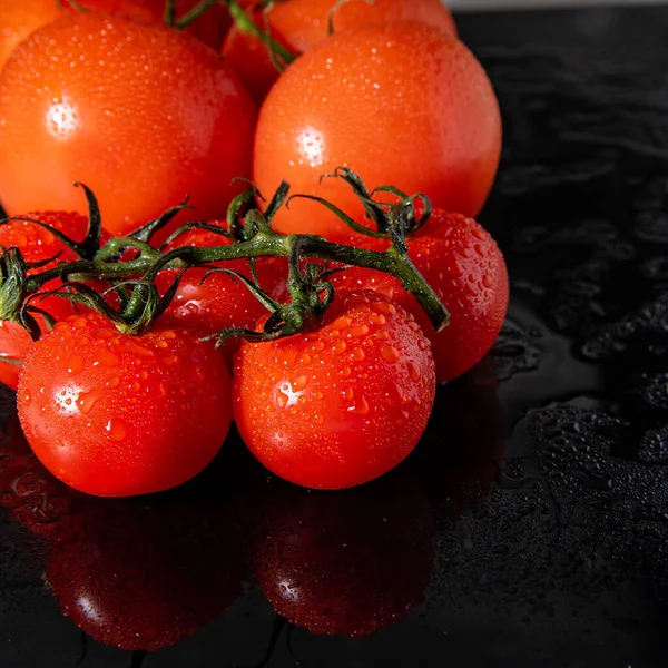 Tomatoes on a branch with water drops, black glass with water stains close-up, copy space, template,