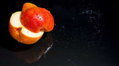 Siyah zemin üzerinde su damlaları ile kırmızı armut kesimi, yakın plan, kopyalama alanı, şablon