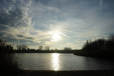 Kışın alçak güneş. Aralık ayında Habermannsee 'deki Kaulsdorfer Baggersee Gölü civarındaki muhteşem bitki örtüsüyle güzel bir manzara. Marzahn-Hellersdorf, Berlin, Almanya  