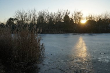 Beautiful sunset over the frozen Wuhlesee lake in February. Marzahn-Hellersdorf, Berlin, Germany 