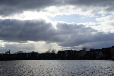 The sun shines through the clouds over the Dahme River in February in the Koepenick district of Berlin, Germany, Europe.                               
