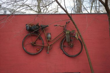 Şubat ayında bir bisiklet ve saksıların yer aldığı bir dekorasyon kırmızı beton bir çiti süslüyor. Berlin, Almanya, Avrupa. 