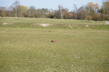 Mart 'ta Schmetterlingswiesen dinlenme alanında kırmızı bir çocuğun uzaktan kumandalı arabası çimlerin üzerinden geçiyor. Marzahn-Hellersdorf, Berlin, Almanya, Avrupa.