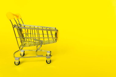 Sarı arka planda boş market arabası. İş anlayışı, alışveriş, kara Cuma satışları..