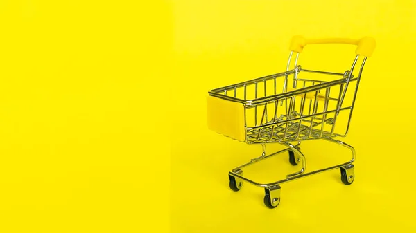 黄色の背景に空のショッピング食料品店カート。ビジネス、ショッピング、黒の金曜日の販売の概念. — ストック写真