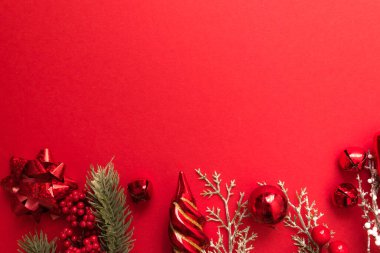 Güzel bir Noel kompozisyonu, hediye paketi, kurdele, hediyeler ve kırmızı arka planda köknar dalları. Kopyalama alanı olan düz.