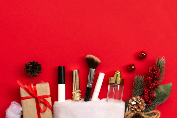 Flat lay composition with makeup products and Christmas decor on red paper background. Xmas, happy new year 2021, female wishes concept. Top view, copy space