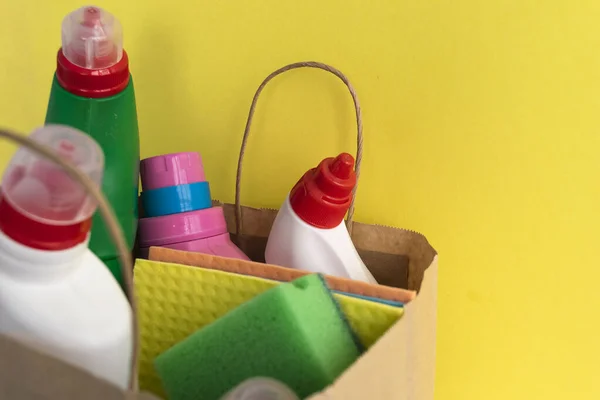 House cleaning supplies on yellow background. Row of plastic bottles with cleaning liquid and sponges, copy space. Cleaning business, production, shopping and delivery donation.