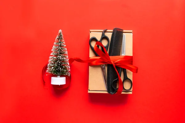 Noel kompozisyonu düzdü. Kırmızı arka planda kuaför aletleri, hediye ve Noel dekoru. Xmas, mutlu yıllar. Boşluğu kopyala.