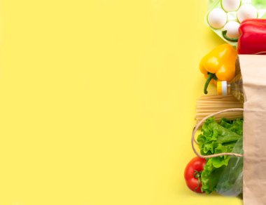 Coronavirus sırasında sağlıklı yemek teslimatı. Kese kağıdında sarı arka plan için gıda bağışı. Muhtelif konserve yiyecekler, tahıllar, makarna ve sebzeler ile karton kutuya yardım et. Gönüllü kutusu. Boşluğu kopyala