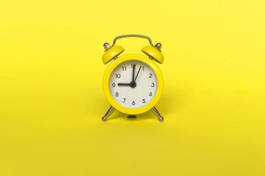 Sarı arka planda izole edilmiş klasik çalar saat. Hayatın dinlenme saatleri. İyi sabahlar. Uyanık kalma kavramı. Düz görünüm kopyalama alanı