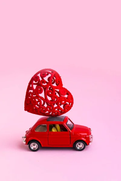 Мінськ, Білорусь - 21 листопада 2020 р.: Рожевий ретро-іграшковий автомобіль доставляє букет-червоний подарунок серця на рожевому тлі. 14 лютого - День святого Валентина. 8 березня - Міжнародний день щасливих жінок. — стокове фото
