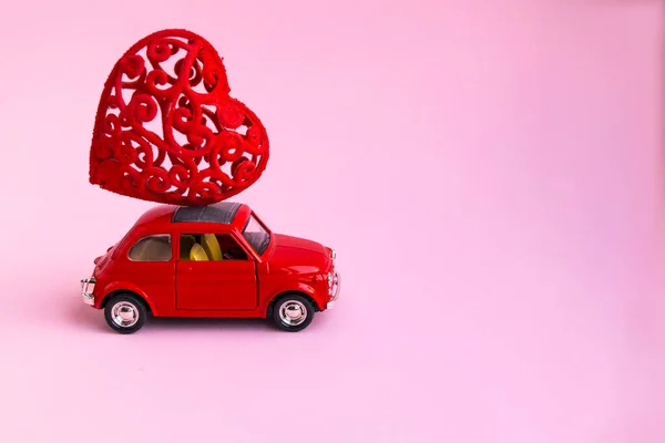 Мінськ, Білорусь - 21 листопада 2020 р.: Рожевий ретро-іграшковий автомобіль доставляє букет-червоний подарунок серця на рожевому тлі. 14 лютого - День святого Валентина. 8 березня - Міжнародний день щасливих жінок. — стокове фото