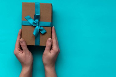 Mavi arka planda fiyonklu güzel bir hediye kutusu olan kadın eller. Yeni Yıl, Noel, doğum günü, Sevgililer Günü, Dünya Kadınlar Günü, Babalar Günü