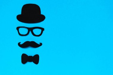 Babalar Günün kutlu olsun. Kağıt dekor şapkası, gözlük, papyon ve mavi arka planda bıyık kompozisyonu