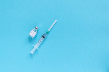 Bir şişe aşı ve mavi zemin üzerinde aşı olan ilaç şırıngası. Aşı ve sağlık hizmetleri kavramı. Metin için boşluk, düz uzanma