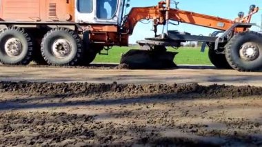 Kırsal bir caddede çakıllı bir yolu dümdüz eden bir not. Endüstriyel makine derecelendirme yolları