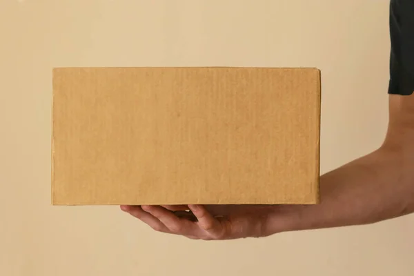 Чоловік доставки в чорному одязі тримає картонну коробку . — стокове фото