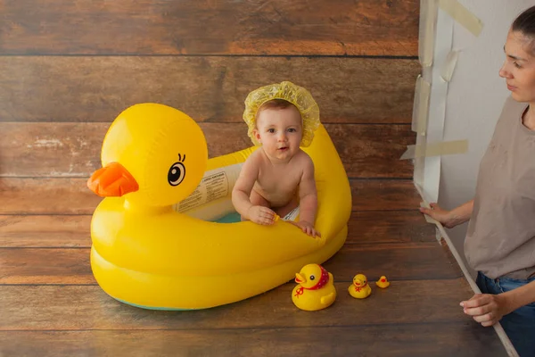 One year old baby girl takes a bath. With yellow rubber duck. — Stock Photo, Image