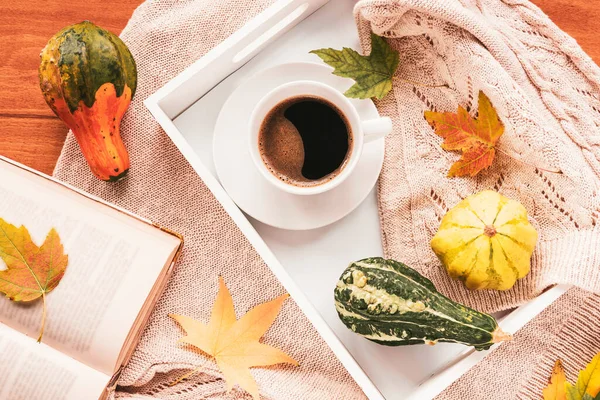 Filiżanka kawy na tacy z jesiennymi liśćmi, książka i sweter z dzianiny. Przytulny dom, jesienny pomysł. Widok z góry — Zdjęcie stockowe