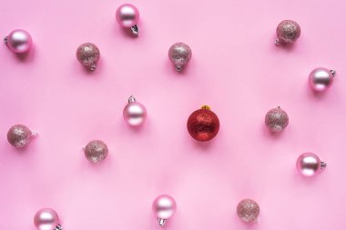 Bir kırmızı noel balosu ve masada bir sürü pembe balo. Noel ya da yeni yıl konsepti. Farklı, dikkat çekici, standart dışı. Üst manzara, düz uzanma.