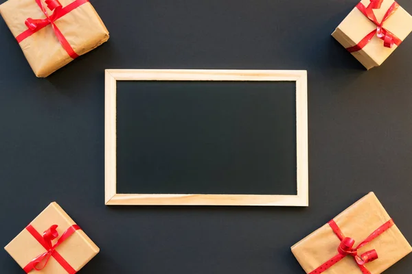 Chalk board on a black background surrounded by gifts. Christmas nad New Year. Holiday shopping on black friday concept, mock up.