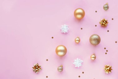 Altın Noel topları, süslemeler ve mücevherlerle dolu pembe şenlikli bir arka plan. Üst görünüm, düz görünüm, kopyalama alanı.