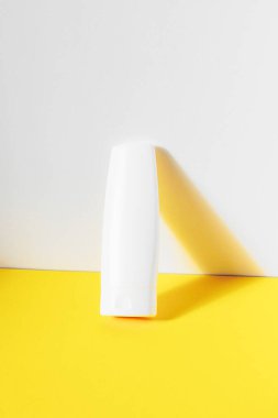 Kozmetik beyaz markasız plastik şişe sarı masada. Doğal cilt bakım ürünleri konsepti.