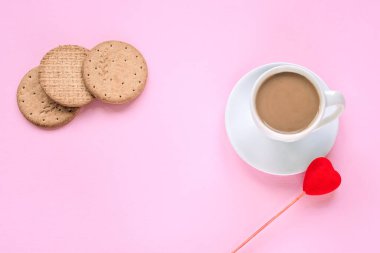 Pembe arka planda bir fincan kahve, kurabiye ve oyuncak kalp. Aşk konsepti, Sevgililer Günü. Üst görünüm, düz görünüm, kopyalama alanı.