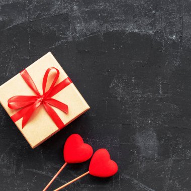 Kutuda hediye ve siyah arka planda iki oyuncak kalp. Sevgililer Günü konsepti. Üst görünüm, düz görünüm, kopyalama alanı.