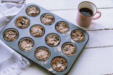 Sağlıklı yulaflı kekler ve beyaz ahşap masada kahve fincanı.